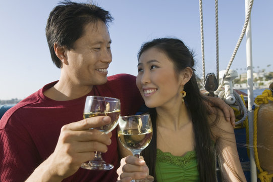 Smiling Couple Toasting Wine Glasses On The Boat