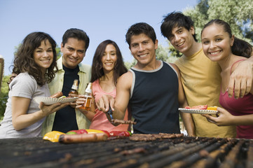 Group portrait of young people gathered around the grill at picnic