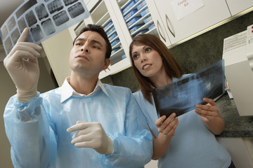 Mature doctor looking at tooth x-ray with colleague holding other x-ray