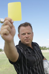 Portrait of mature soccer referee showing yellow card to warn a player