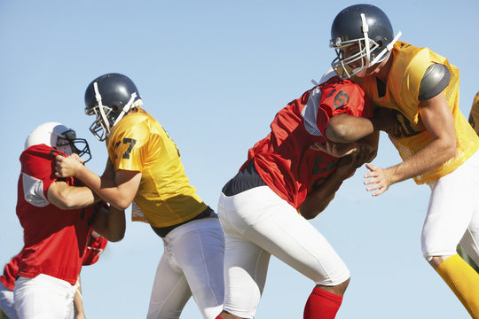 Rugby players tackling each other against clear sky