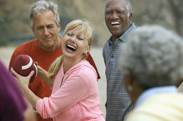 Group of adult multiethnic friends playing American football on the beach