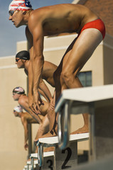 Side view of male swimmers lined up at the starting blocks