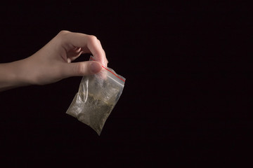 hand with pack of maijuana on black background