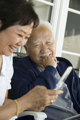 Senior couple using mobile phone smiling outdoors