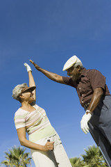 Happy African American couple giving high-five on golf course