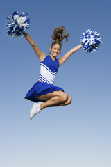 Full length of a young cheerleader jumping against clear sky