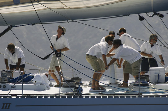Side view of crew members working on sailboat