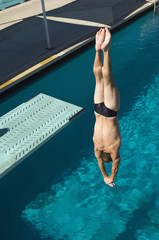 Caucasian male swimmer diving upside down into the pool