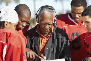 Football players and coach discussing strategy together - Powered by Adobe