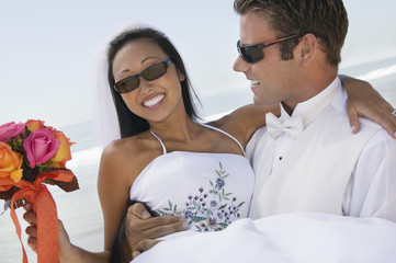 Groom carrying bride outdoors (close-up)