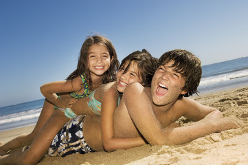 Fototapeta premium Brother and sisters having fun at beach on a sunny day