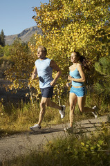 Man and woman jogging on a path in the forest