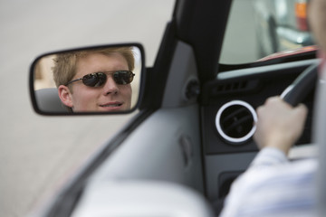 Reflection of young man in side view mirror of car