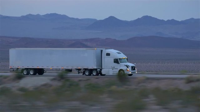 CLOSE UP: Freight semi truck driving and transporting goods on empty highway