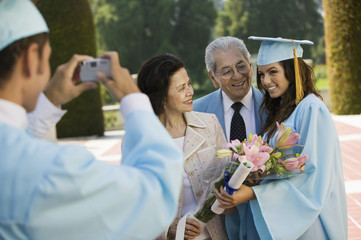 Graduate taking picture of other graduate and grandparents outside
