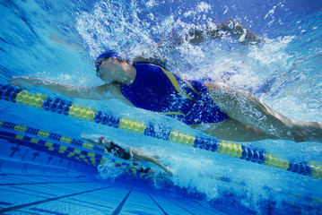 Low angle view of female swimmers gushing through water in pool