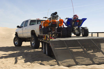 Quad bikes on trailer behind pickup truck in desert - obrazy, fototapety, plakaty