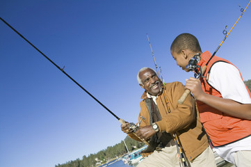 Happy grandfather and grandson fishing together on a sunny day