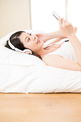 Obraz na płótnie Canvas asian woman listen music looking smart phone with headphones