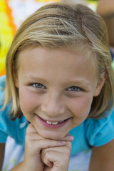 Closeup portrait of a beautiful little girl smiling with hands on chin