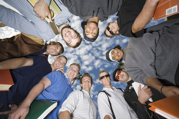 Group of male friends forming huddle against sky
