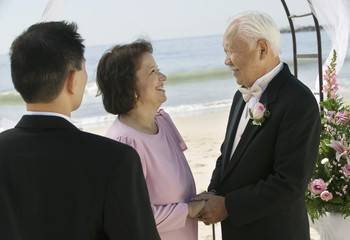 Groom with parents at beach wedding