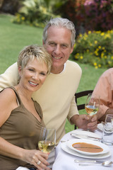 Portrait of happy mature couple at table celebrating with wine