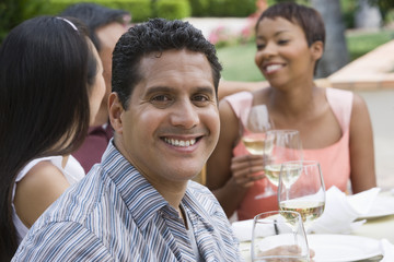 Portrait of happy mature man with friends holding wine glass