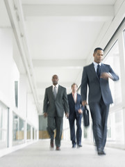 Blurred motion of multiethnic businesspeople walking in office corridor