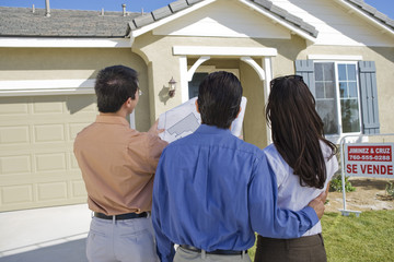 Fototapeta premium Rear view of couple with real estate agent explaining housing plan