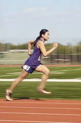 Obraz premium Side view of an Asian female athlete running on race track