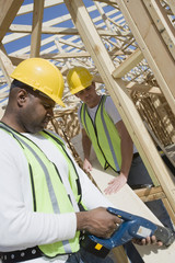 Manual workers using drill at construction site