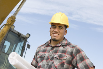 Portrait of a happy male architect with blueprint at construction site