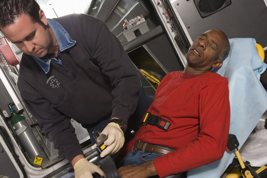 Male EMT Professional Taking Care Of A Senior Man Inside Ambulance