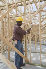 Fototapeta na wymiar Manual worker hammering nail into framework at construction site