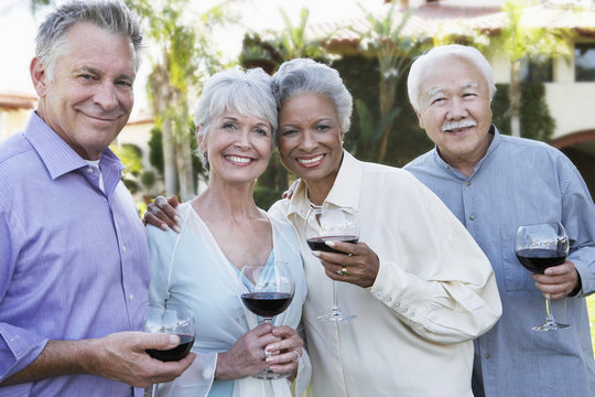 Portrait of happy senior couples standing outside with wine glasses