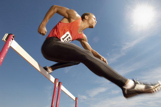 Low Angle View Of Determined Male Athlete Jumping Over A Hurdles