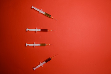 Hand in glove with syringe on red background.