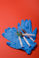 Hand in glove with syringe on red background.