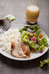 Italian salad with rotisserie chicken and white rice with Italian dressing on dark wood