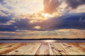 Fototapeta na wymiar Wooden table at riverside on beautiful sunset background.