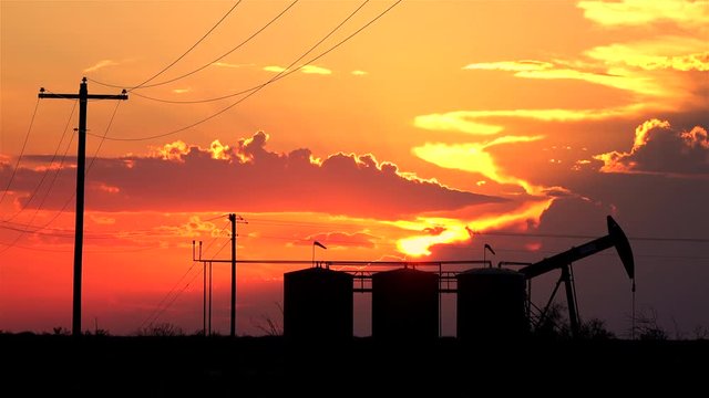 Oil pump jack containers and electrical wiring at amazing golden sunset