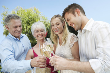 Happy young and senior couple toasting champagne flutes outdoors