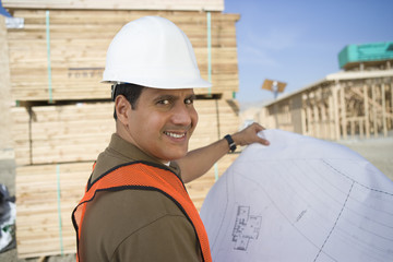 Portrait of a happy architect holding blueprint at construction site