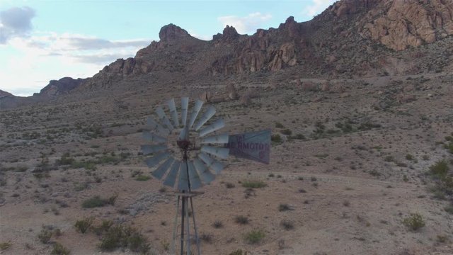 AERIAL: Big vintage windmill under beautiful rocky mountains