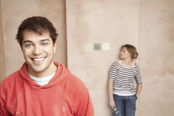 Fototapeta premium Portrait of happy man with woman looking at color samples on wall in unrenovated house