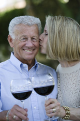 Portrait of happy senior couple celebrating while wife kissing husband on cheek
