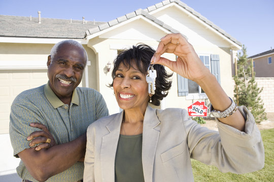 Portrait of happy African American couple with key in front of new house