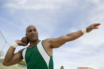 Closeup of a shot putter preparing to toss shot put against the sky